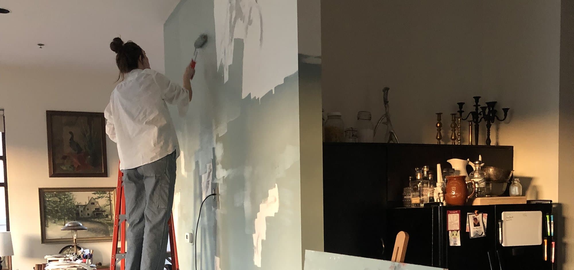 Haley roller-painting a wall on the left of a split image with antique home belongings on the right