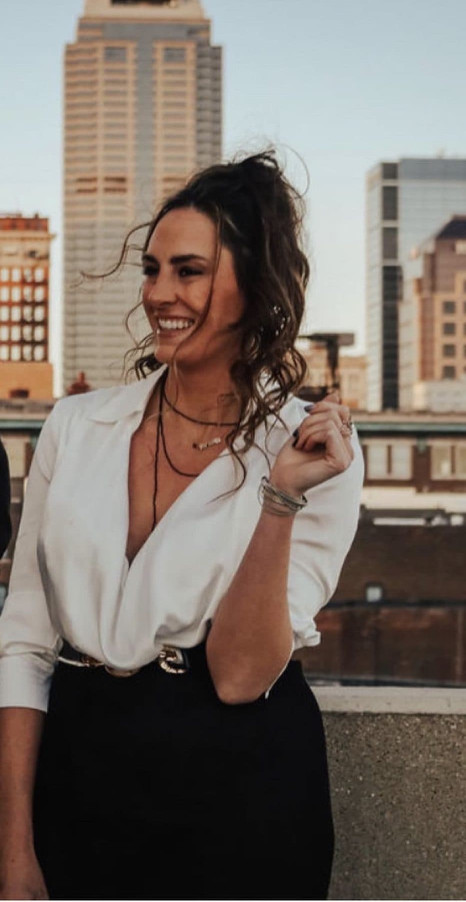 White button-down and black skirt on a rooftop, downtown Indianapolis behind.