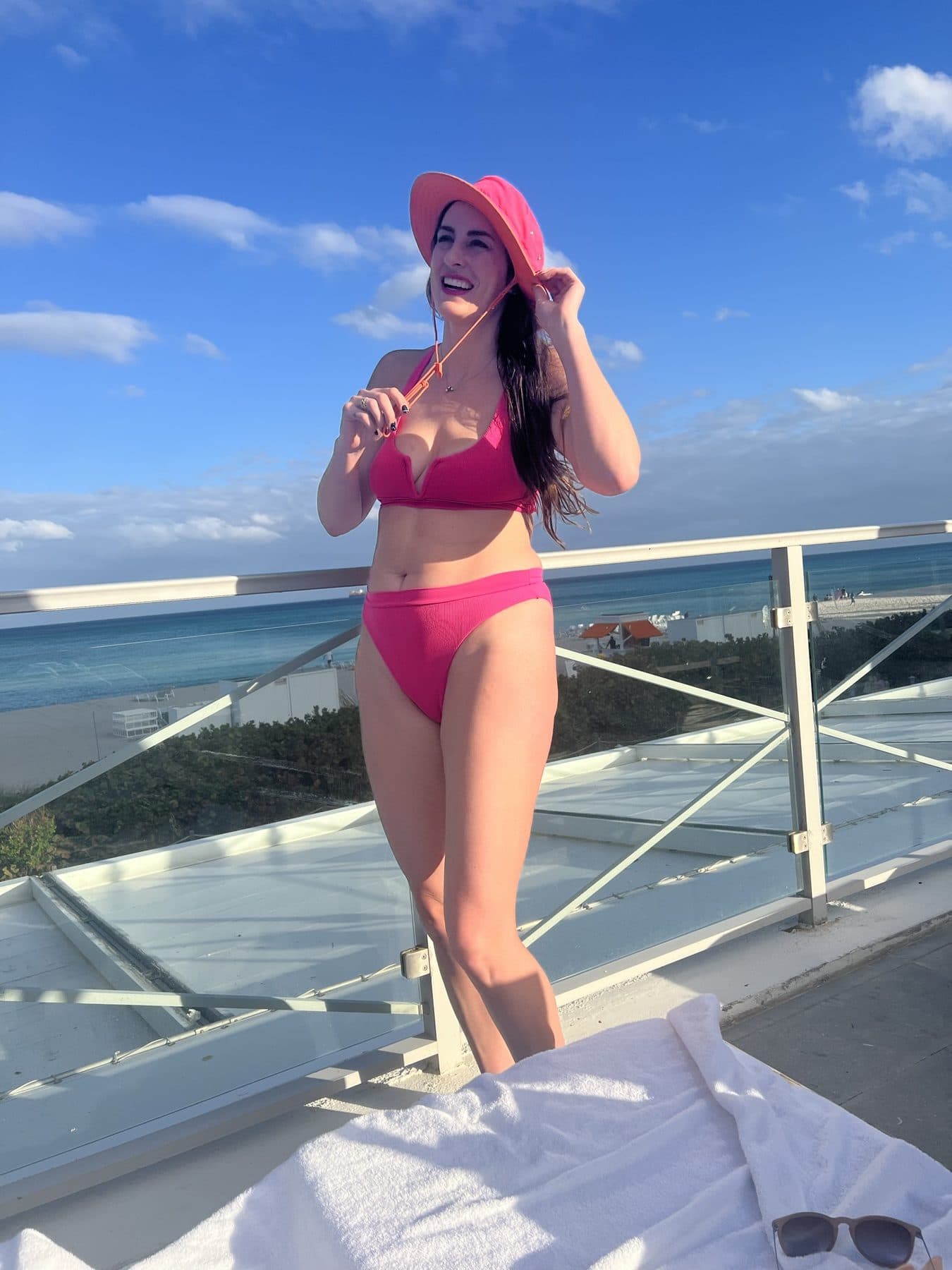 Pink swimsuit and straw hat, framed against a bright sky.