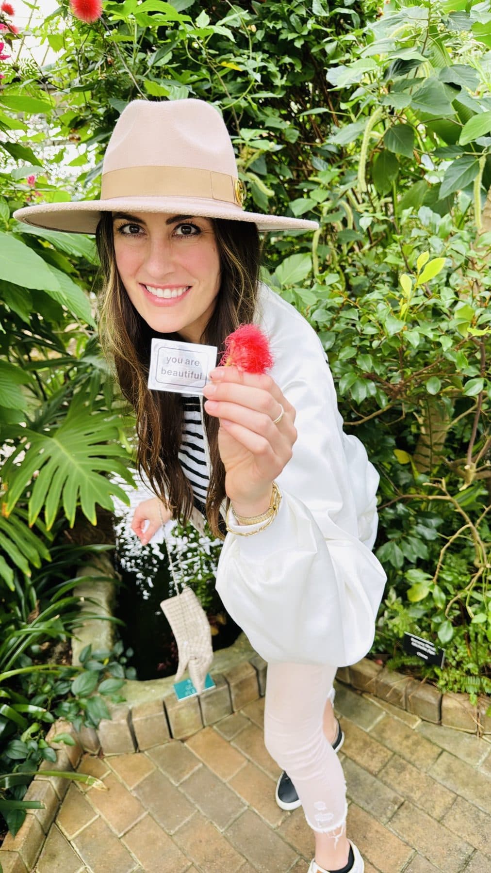 Tan hat and white shirt among greenhouse blooms.