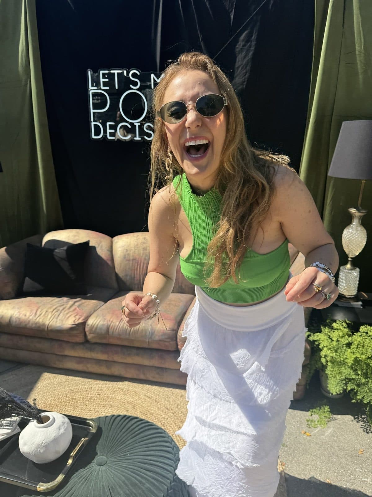 Haley in a green halter and white skirt, laughing mid-dance in front of the lounge sofa.