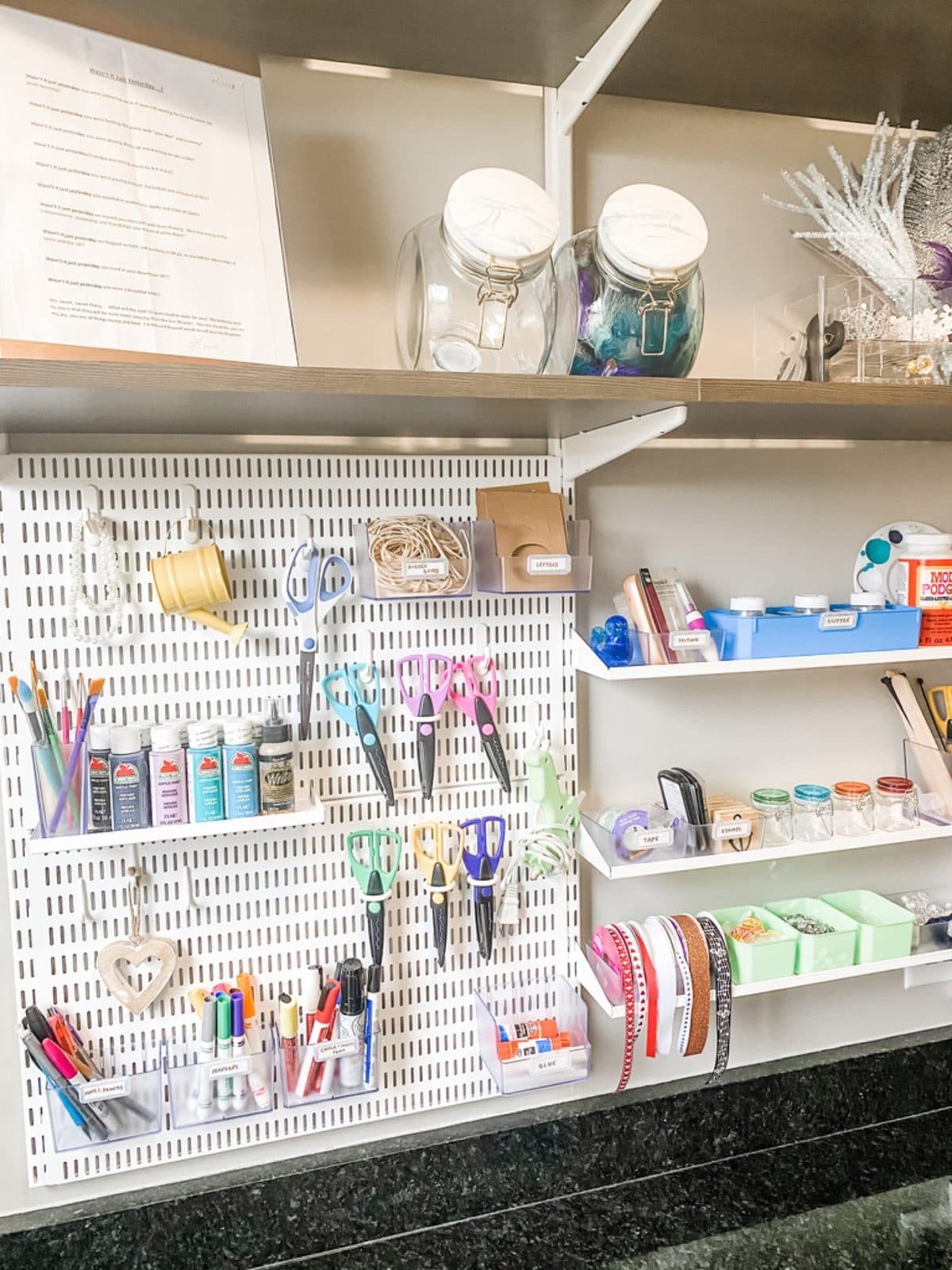 A narrow linen closet with rolled towels in wire baskets, labeled jars, and a wire hamper on the floor.