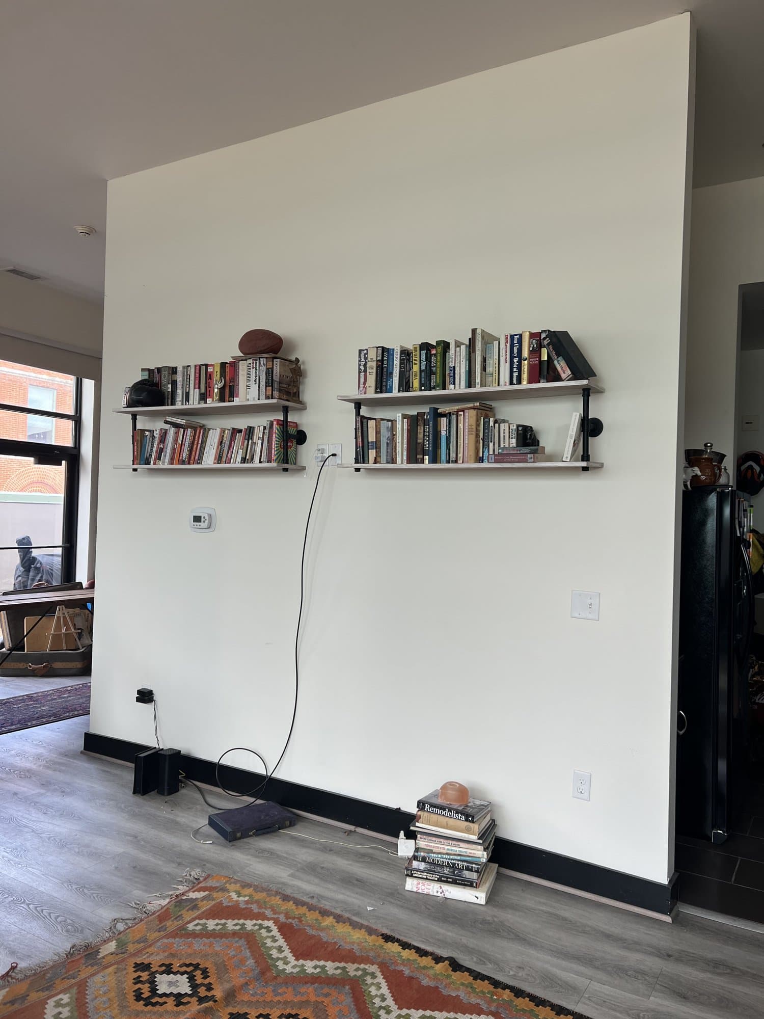 Before, a flat white studio wall with floating bookshelves and a green console, no focal point.