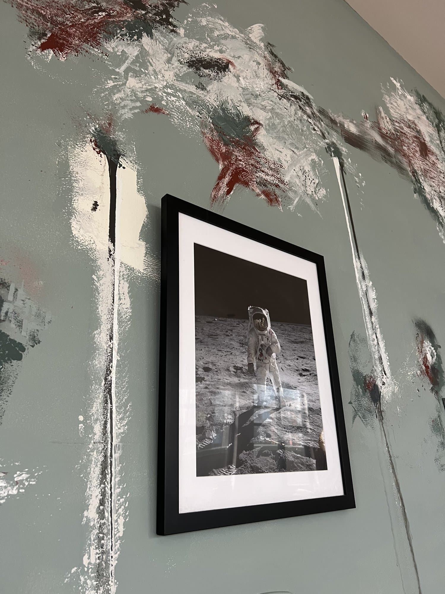 Close detail of the troweled plaster, layered teal, white, and rust worked around a black-framed print.