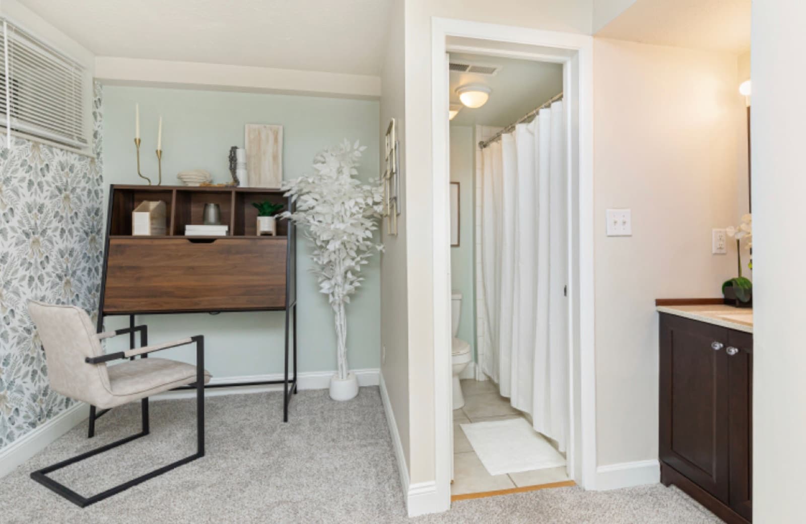 Work nook with a walnut secretary desk against a soft-green wall, leading to the bath.