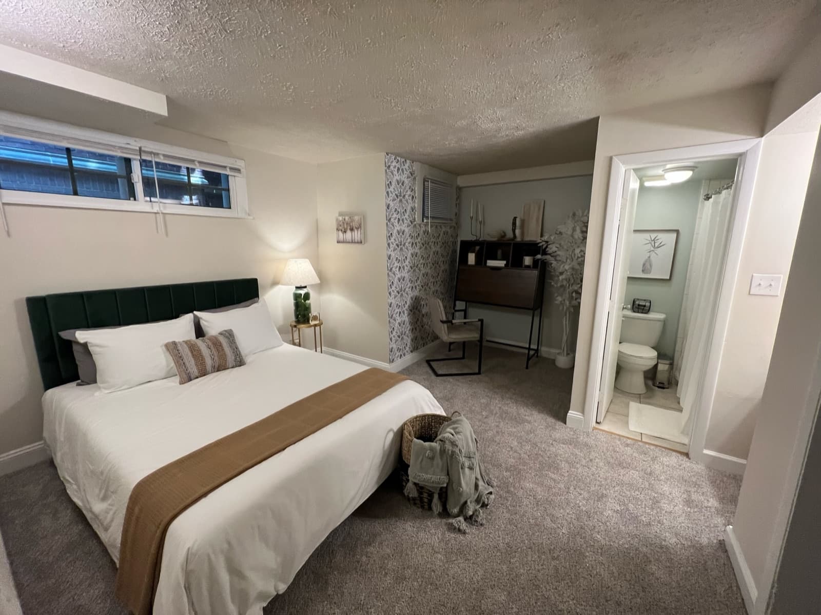 Bedroom suite with workspace nook and ensuite bath visible beyond the staged bed.
