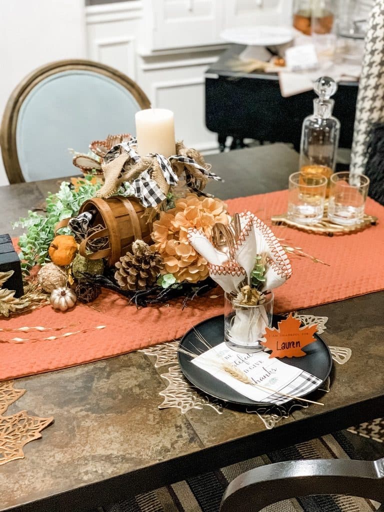A candle-and-basket centerpiece with gingham ribbon, dried hydrangea, and mini pumpkins running the length of the runner.