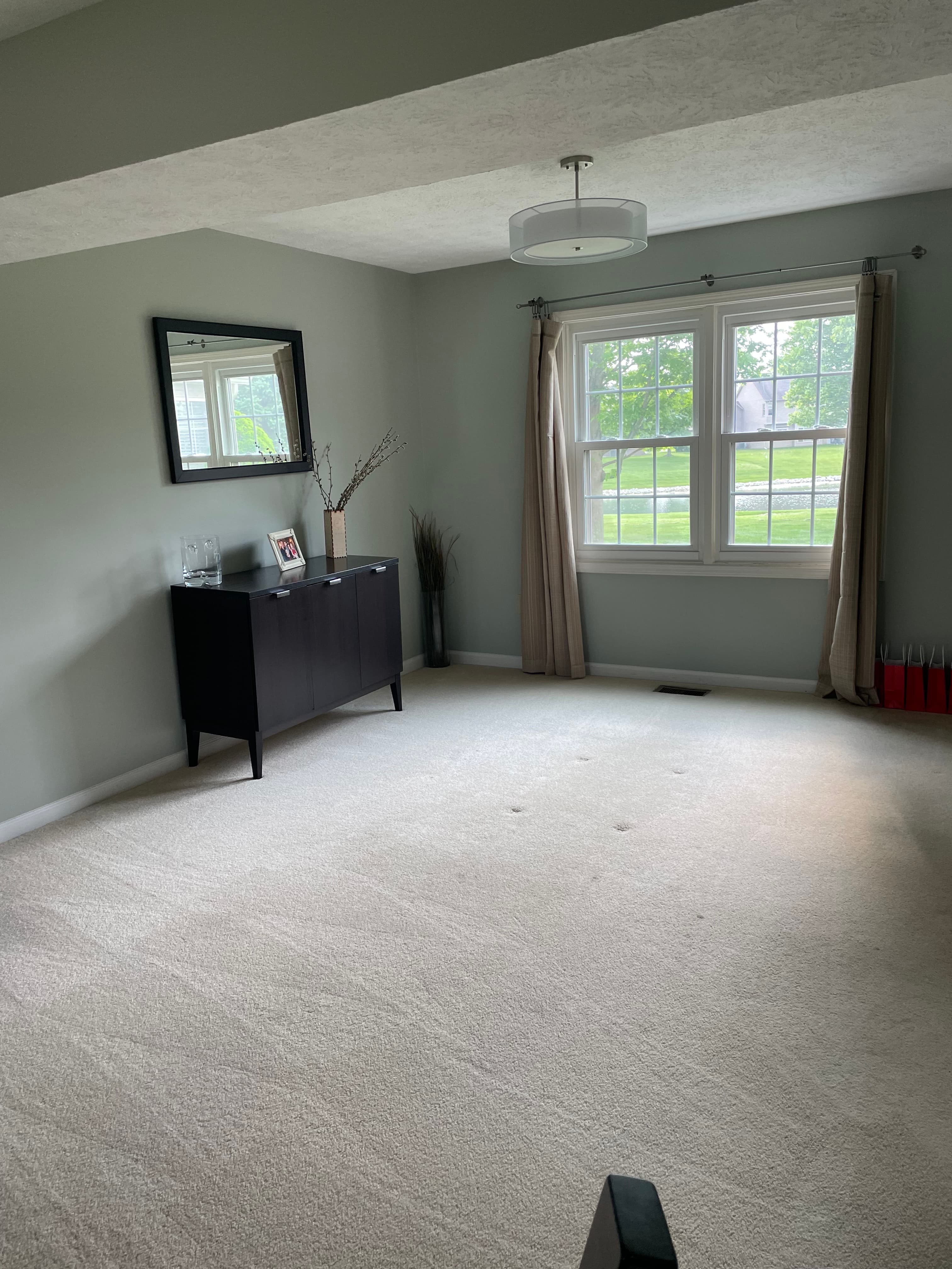 The home before, a plain furnished spare room with a dark dresser and mirror, no purpose yet.