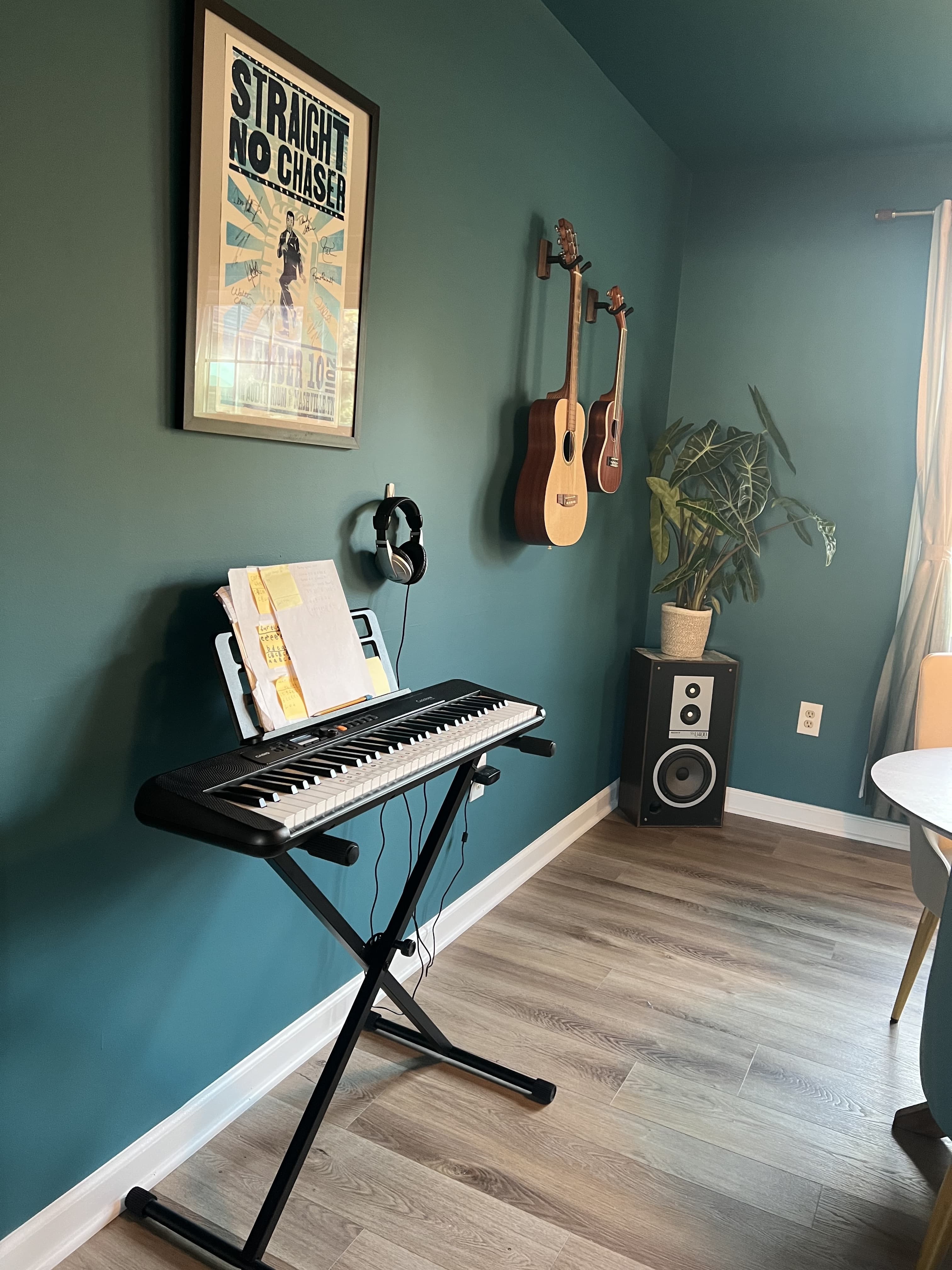 The music studio corner, guitars on floor stands beneath a concert poster.