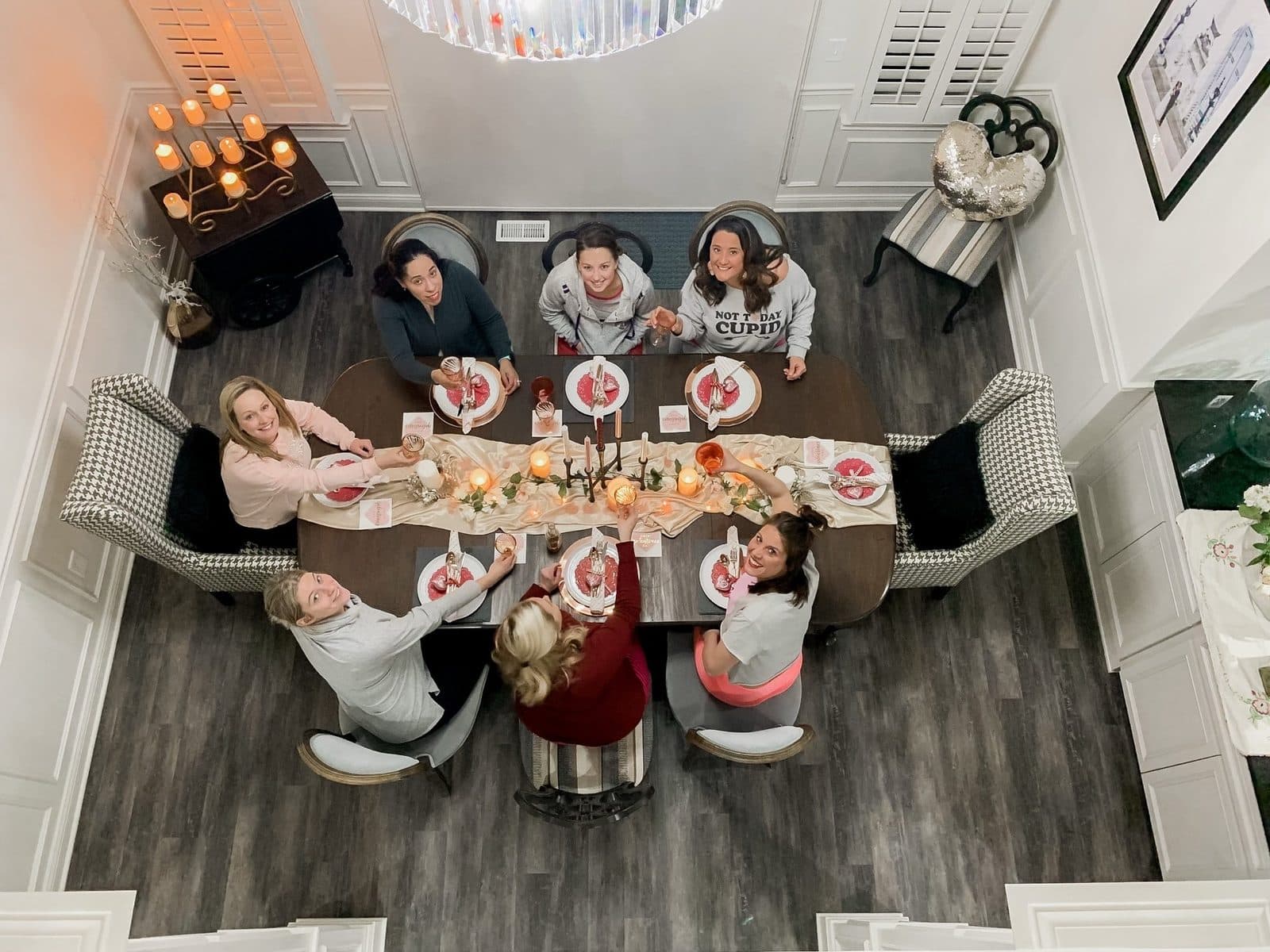 Glasses raised: the whole table toasting up at the camera from the double-height dining room.