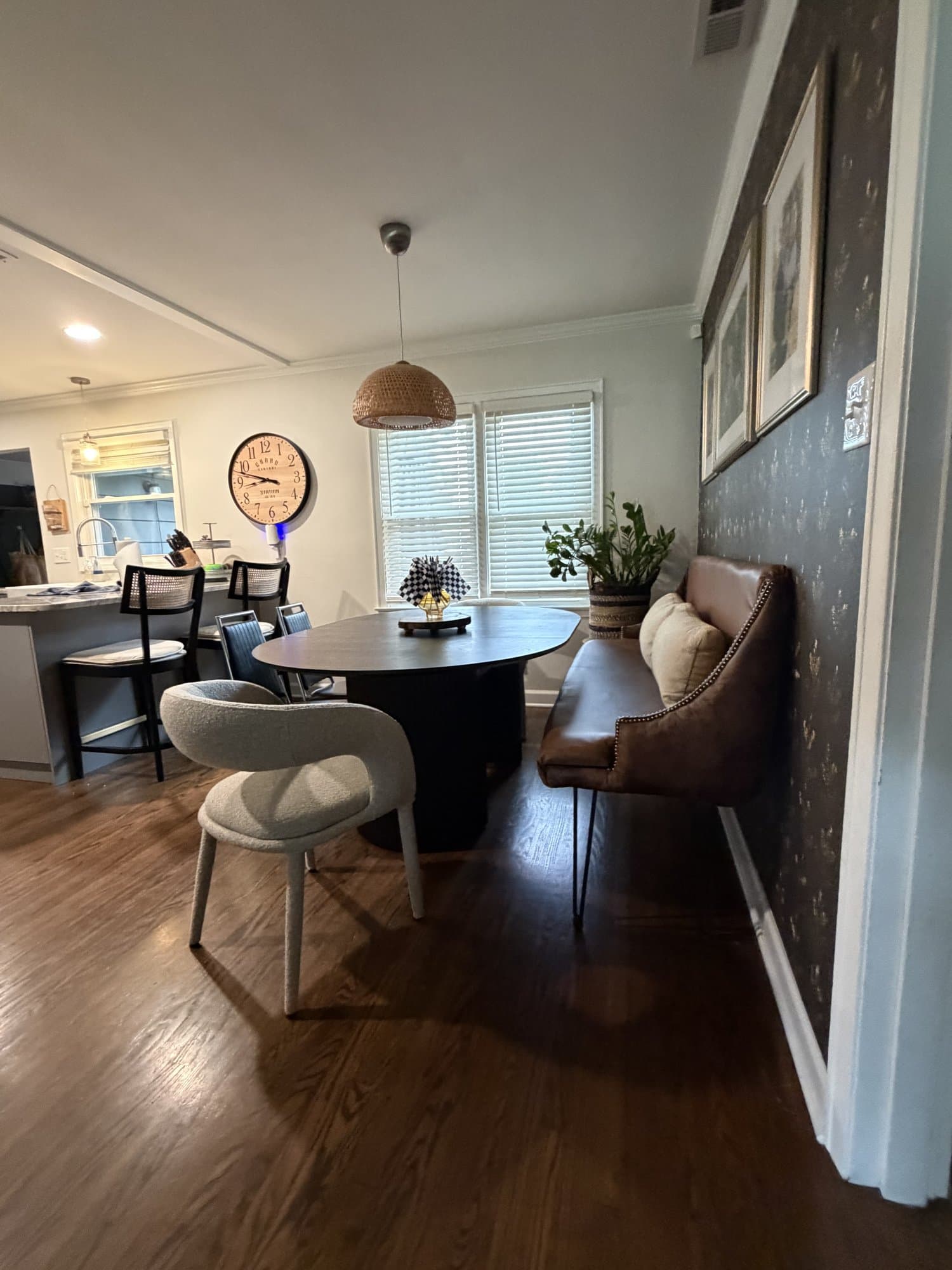 The nook by the window, pendant light, pedestal table, and cane chairs against the papered wall.