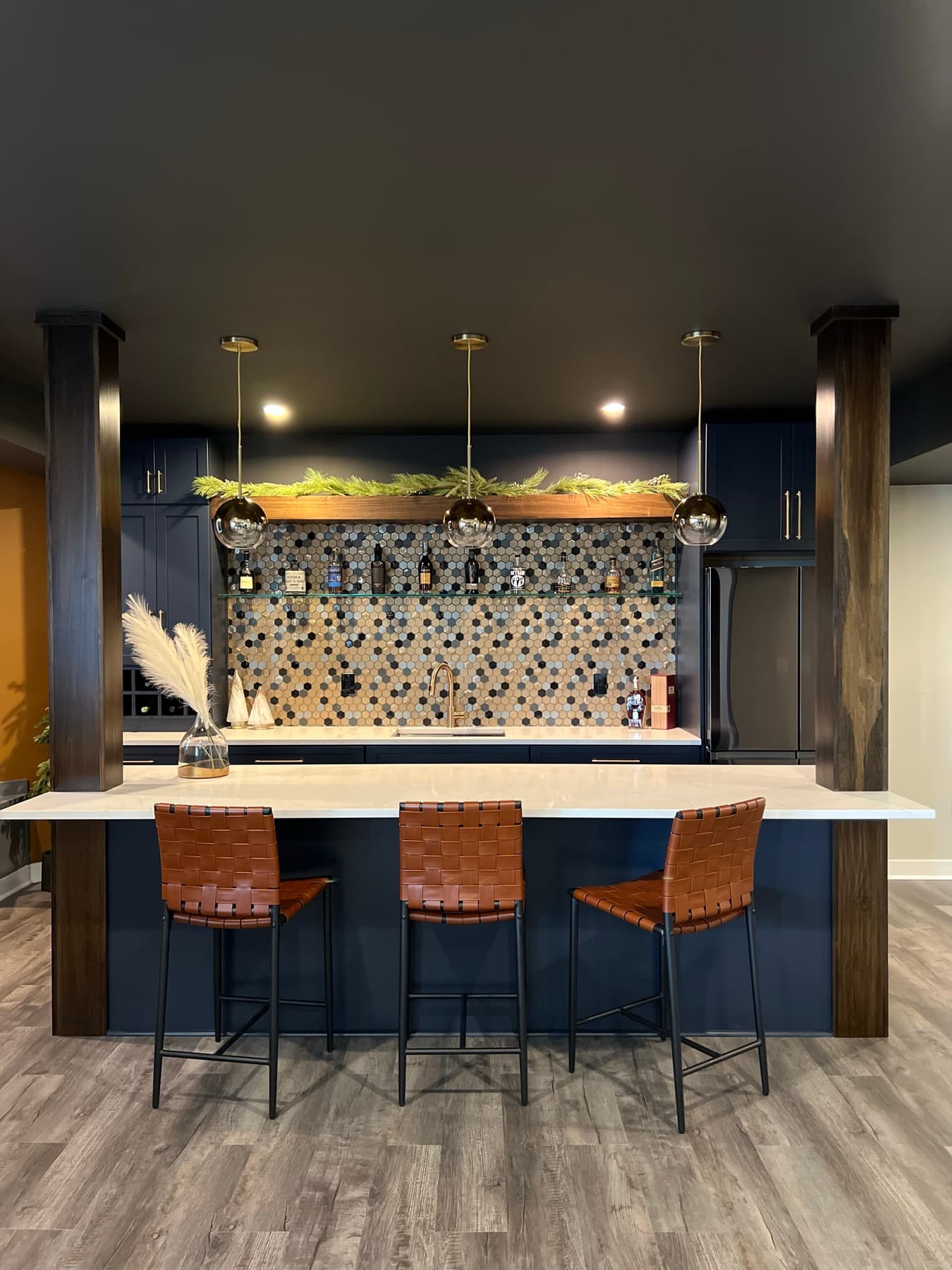 The bar from the room, walnut top, brass rail, pendant lights.