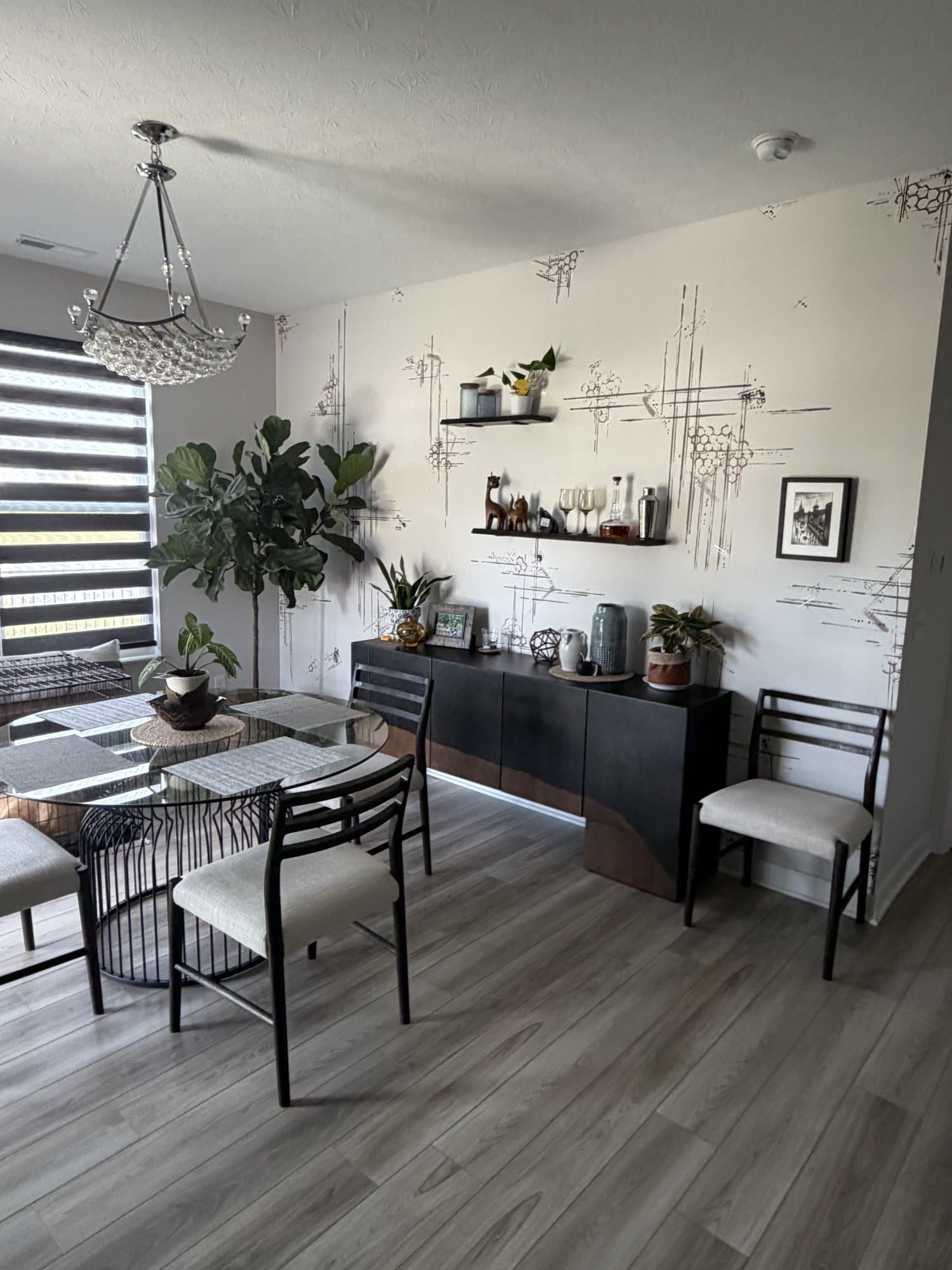 Second angle on the dining area, the sketched mural wrapping the wall behind layered seating and greenery.