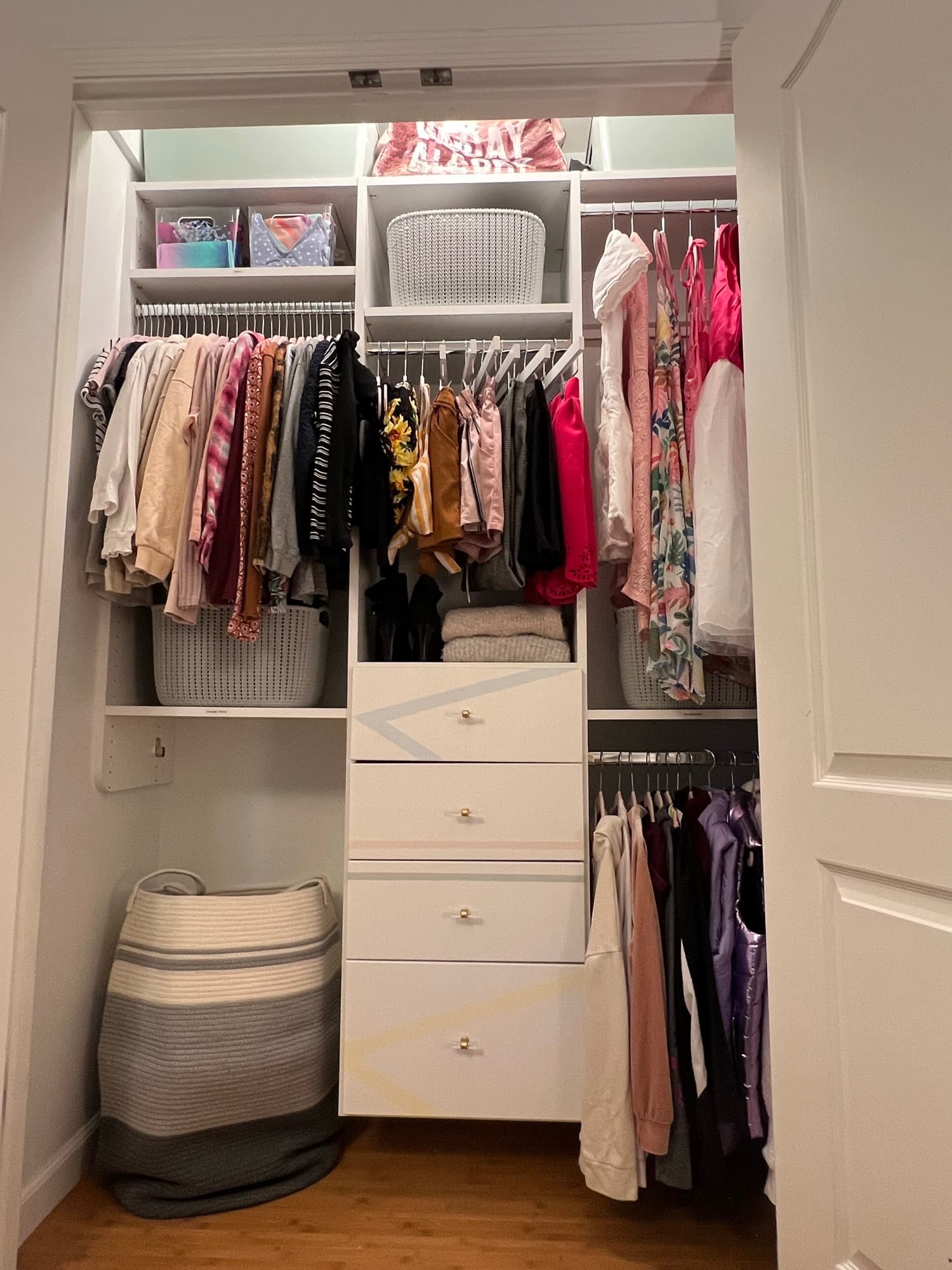 The reworked closet, clothing folded and color-sorted into cubbies and bins beneath a row of cabinet doors.