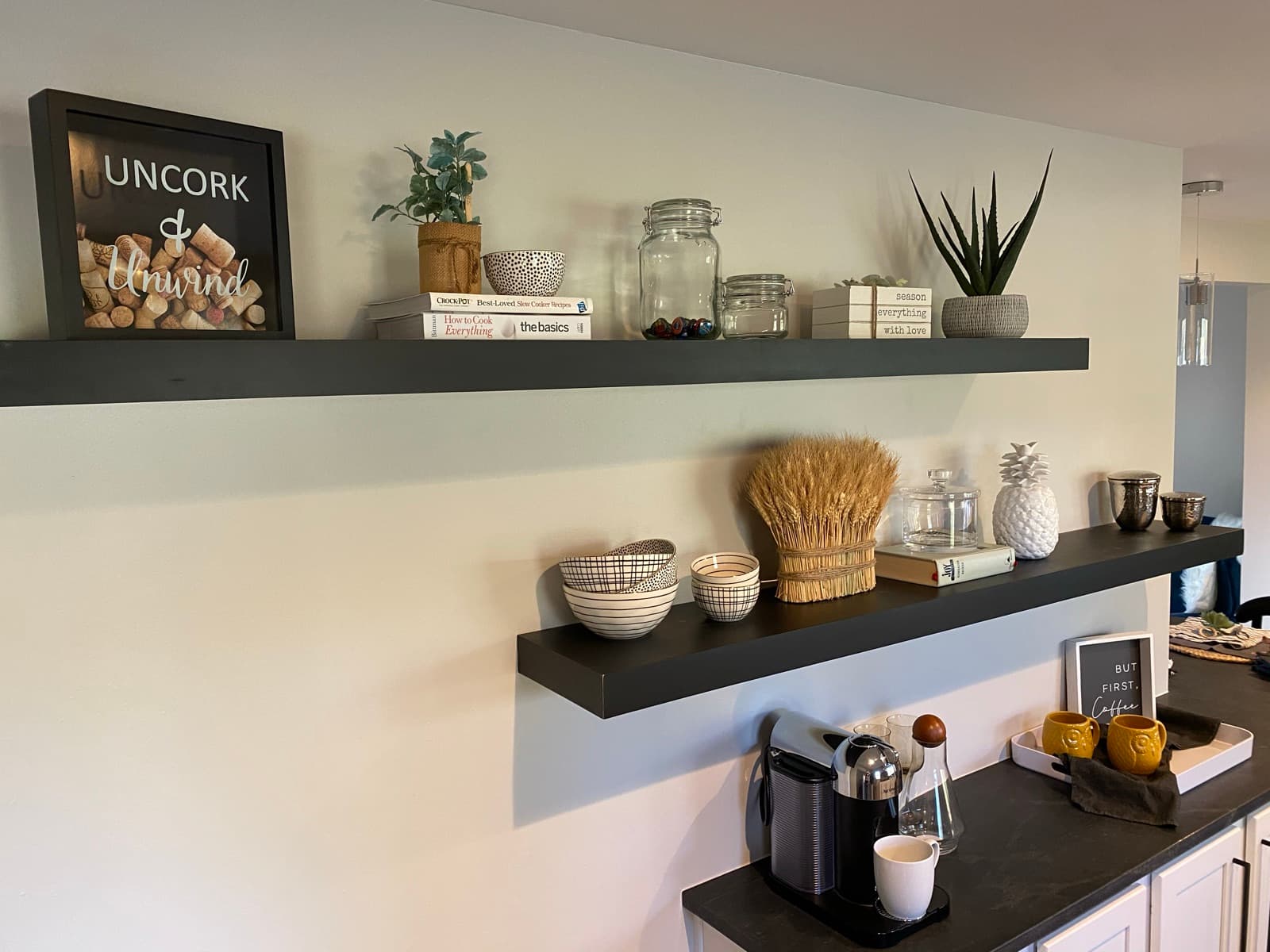 Floating-shelf coffee and wine bar with an 'Uncork & Unwind' print and curated ceramics.